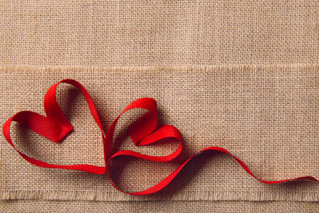 Two Hearts on Sackcloth Burlap Background. Valentine Day or Wedding Love Concept. Ribbon Shape as Joined Coupleの写真素材