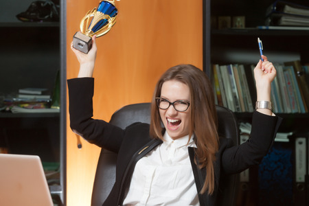 Young beautiful woman sitting on the black leather chair and happy for winの写真素材