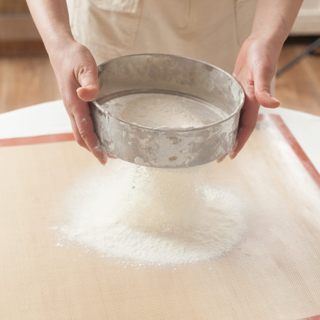 Chef sifting baking powder into dough for making cake
