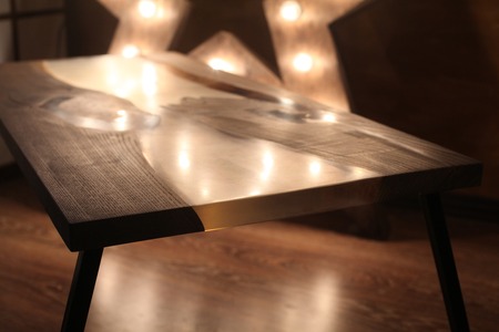 Wood and epoxy table with star lamp and metal legs in wooden interiorの写真素材