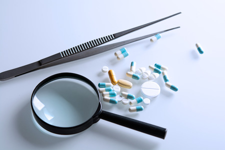 medicines and magnifying glass with tweezers on the steleの写真素材