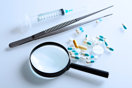 medicines and magnifying glass with tweezers on the steleの写真素材