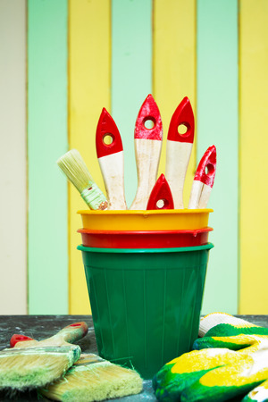 Painting brushes in pots against the painted wallの写真素材