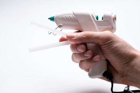 glue gun and two pins in the handの写真素材