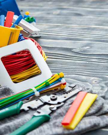 Tools for electrician and cables on gray wooden surface