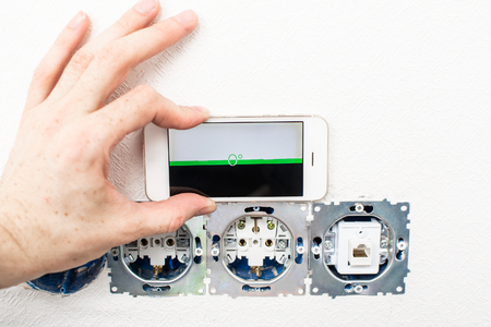 the process of installation electrical sockets level with a smartphoneの写真素材