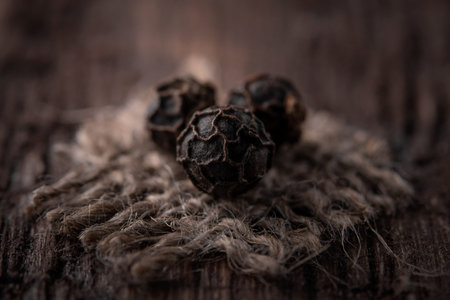 grains of black pepper on jute fabric close-up