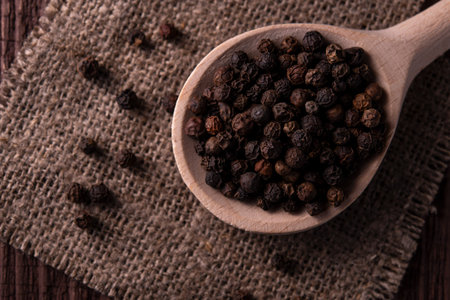 spoon with black pepper on jute fabric