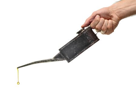 Male hand holds holding an old oil can isolated on a white background close up.の写真素材