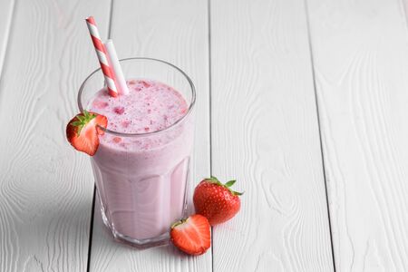 Strawberry protein shake on a white wooden background. Fresh milkshake with strawberries on a light table. A glass of strawberry smoothie.の写真素材