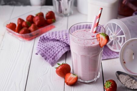 Strawberry protein shake on a white wooden background. Fresh milkshake with strawberries on a light table. A glass of strawberry smoothie.の写真素材