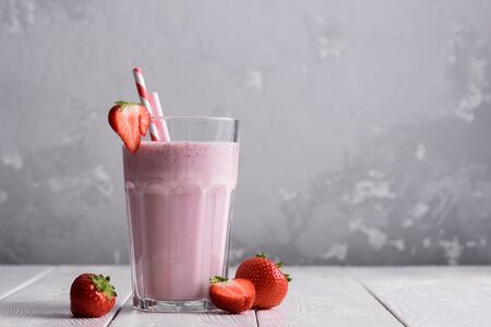 Strawberry protein shake on a white wooden background. Fresh milkshake with strawberries on a light table. A glass of strawberry smoothie.の写真素材