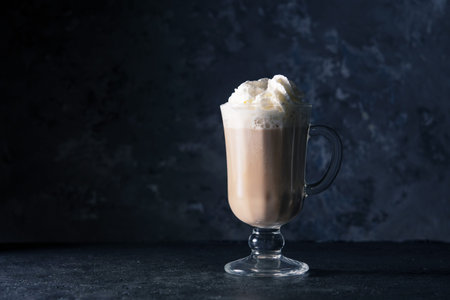 Glass of cappuccino on a dark background with place for text.