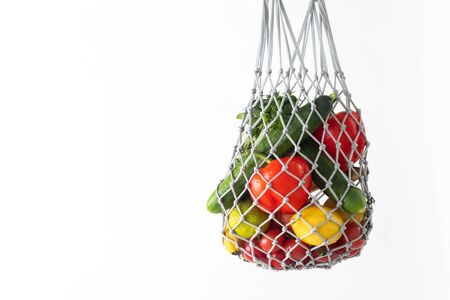 String bag with organic fruit and vegetables isolated on a white background. Mesh shopping bag with fruits and vegetablesの写真素材