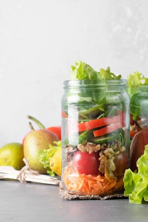 Healthy homemade mason jar salad with fresh pear tomatoes, carrots and herbs. Vegetarian concept.の写真素材