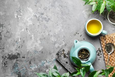 A cup of green tea in a blue cup on a gray concrete background. Cup of green tea with a teapot on a gray concrete background with copy space. Top viewの写真素材