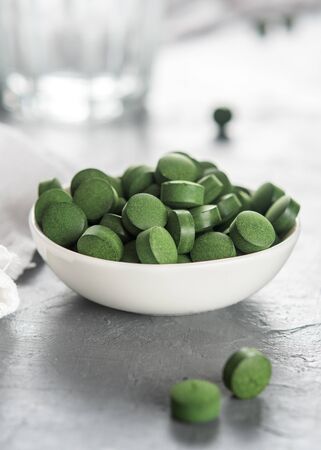 A cup of spirulina or chlorella tablets on a concrete background.の写真素材