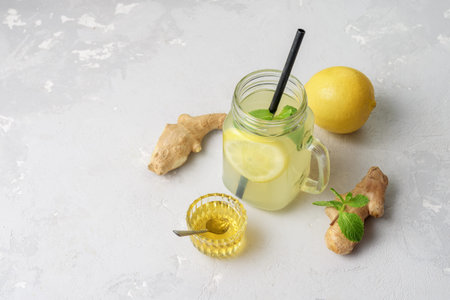 Glass with ginger water and ingredients on grey concrete surface. Top view.