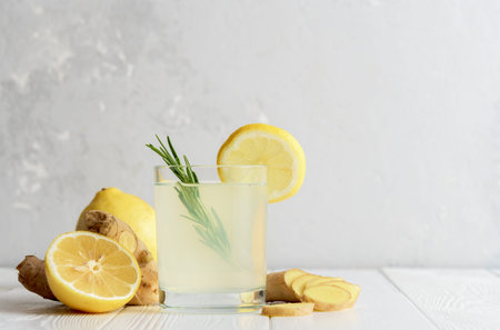 Glass of ginger water with lemon on concrete surface.