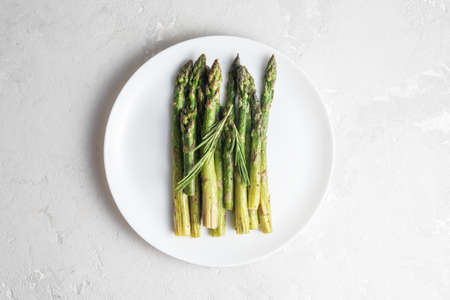 Deliciously cooked asparagus in a white plate on a concrete surface. Top view.の写真素材