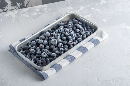 Frozen blueberries in a metal tray on a concrete background.の写真素材