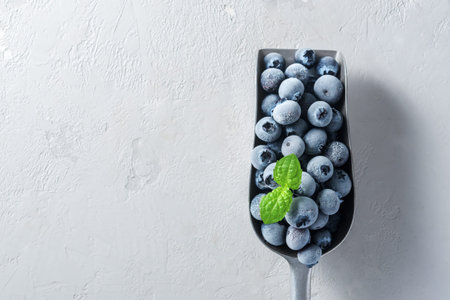 A scoop of frozen blueberries on a concrete surface.