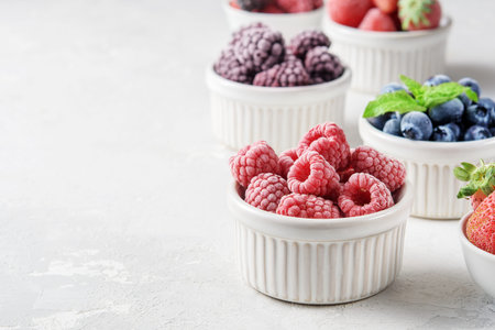 Frozen berries in small bowls on a concrete background from copies of space.