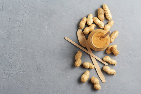 Homemade peanut butter in a glass jar on a concrete surface. Top View