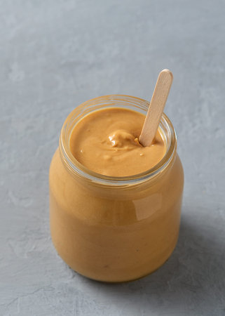 Homemade peanut butter in glass jars on concrete surface.