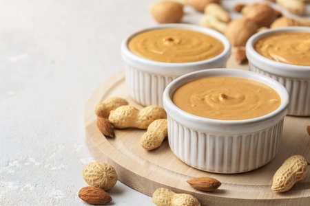 Walnut butter made of peanuts, almonds and walnut on a gray background.