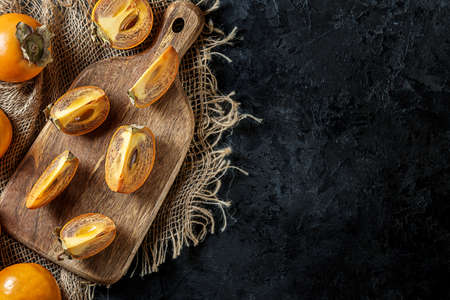 Juicy persimmon slices on a black concrete background with copies of space.の写真素材