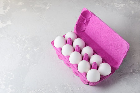 White chicken eggs in pink cardboard packaging with copies of space.