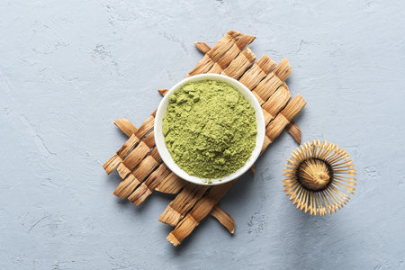 A bowl of matcha tea powder with a whisk on a concrete background. Top view.の写真素材