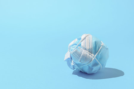 The concept of ending a pandemic. Crumpled medical mask on blue background.