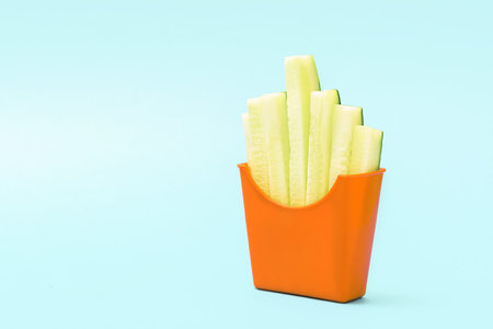The concept of healthy eating. A cup of french fries with sliced cucumbers.