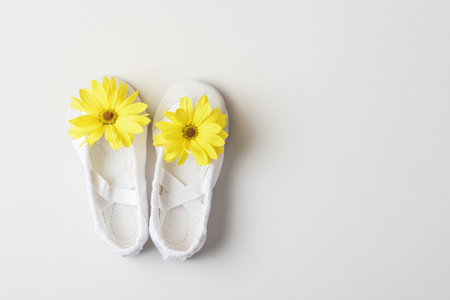 White ballet flats with yellow flowers on a white background with copy space.