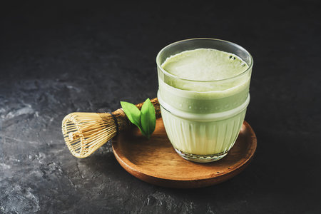 A glass of matcha tea on a dark concrete background with copy space.