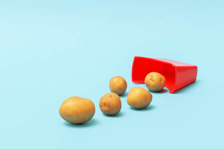 The minimalist concept of junk food. Scattered natural potatoes from a red cup on a blue background.の写真素材