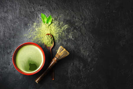 A bowl of matcha tea with scattered powder on a dark background with copy space. Top view.の写真素材