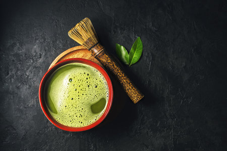 Bowl of matcha tea with whisk on dark background with copy space. Top view.の写真素材