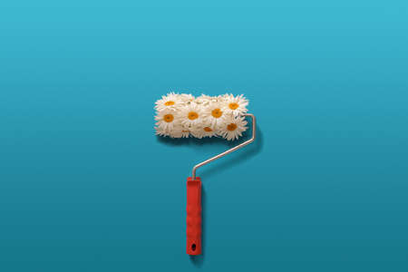 Creative composition of camomiles and paint roller on blue background.の写真素材