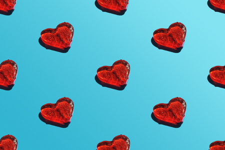 A repeating heart pattern on a blue background with a sharp shadow.の写真素材