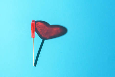 Lollipop in the form of a heart on a blue background with a sharp shadow.の写真素材