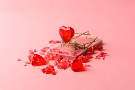 A glass heart in a mousetrap on a pink background. A creative concept for Valentine's Day.の写真素材