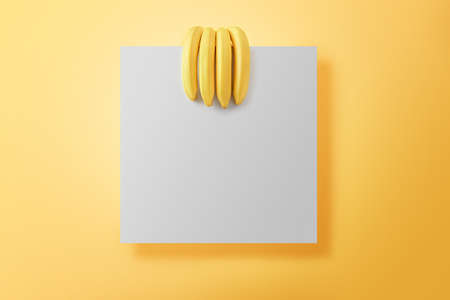 Ripe bananas on yellow background with copy space. Bunch of bananas in the form of a human hand holding a square note.の写真素材