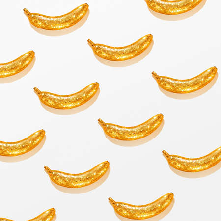 Creative pattern of a golden banana on a white background. Creative background.の写真素材