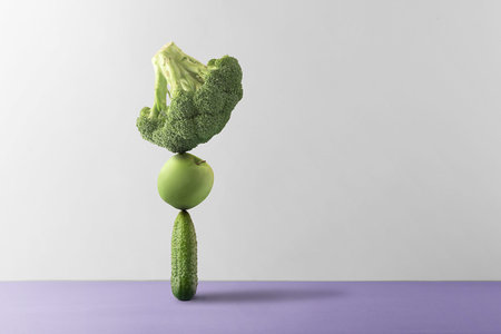 Concept of nutritional balance. Fresh fruits and vegetables are balanced against a gray background.の写真素材