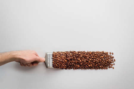 Creative coffee composition on a gray background. A man's hand with a brush paints with coffee beans. Top view.の写真素材