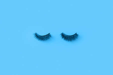 Creative blue Monday concept. Glued eyelashes on a blue wall.の写真素材