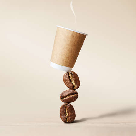 Coffee cup balancing on coffee beans. Mockup of a coffee cup on a beige background.の写真素材